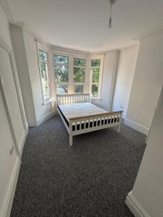 A bright double bedroom featuring a large bay w...