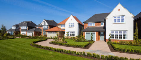 Modern detached houses with white and brick exteriors, manicured lawns, and paved walkways at Newton