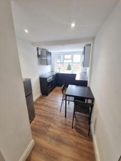 Bright modern kitchen with L-shaped dark cabine...