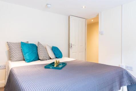 Bright, neatly styled bedroom with a neatly mad...