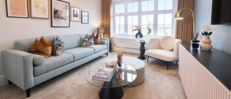 Modern living room with a light grey sofa, white armchair, round coffee table, framed art on the wal