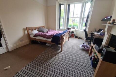A cozy single bedroom with a large bay window a...