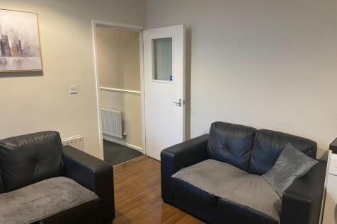 Neat living area with two black leather sofas, ...