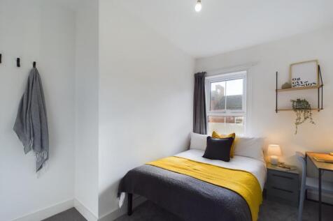 A bright and welcoming bedroom featuring a comf...