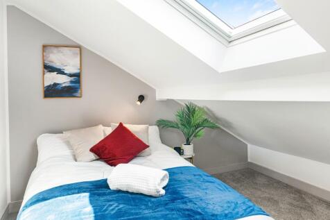 Bright bedroom with skylight and cozy bed...