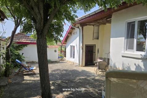 View of courtyard featuring a tree, white walls, tiled roof, and a lounge chair with blue towel.
