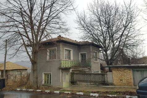 View of the two-storey Bulgarian house showing the balcony and surrounding bare trees in winter