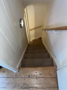 Carpeted staircase with wooden handrails...