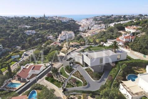 Aerial drone view of a modern luxury villa for sale in Carvoeiro Algarve with private pool landscaped gardens and distant sea views