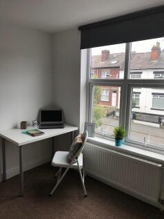 Bright, tidy bedroom corner with a large sash w...