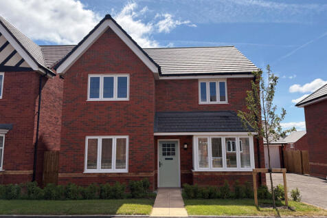 A modern red brick house with white-framed windows and a light green door stands on a paved driveway