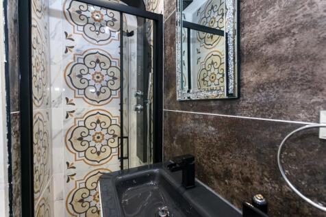 Stylish bathroom with patterned tiled shower, s...