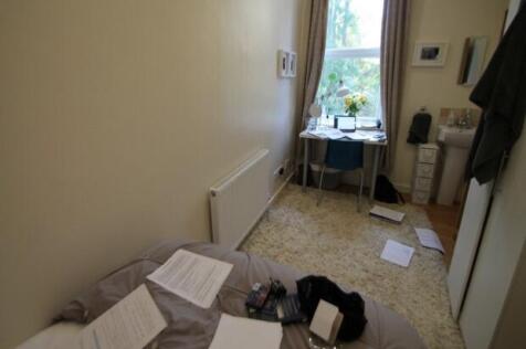 A modest bedroom with a window allowing natural...