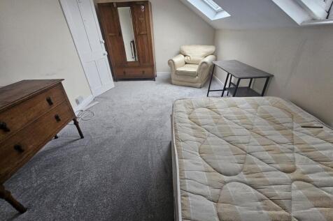 Bright attic bedroom with sloped ceilings and s...