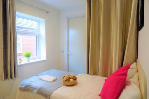 Cozy single bedroom featuring a bright window w...