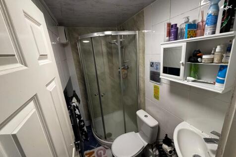 Compact tiled bathroom with a corner glass show...