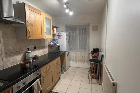 Modern galley kitchen with light wood cabinets,...