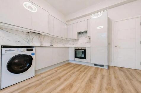 Bright modern kitchen with white cabinetry, int...