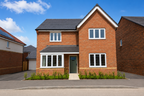 A modern brick house with white-framed windows stands on a paved driveway in the foreground