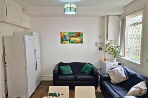 Bright, tidy lounge with two black leather sofa...