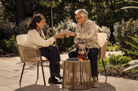 a man and woman sitting on a bench with a drink