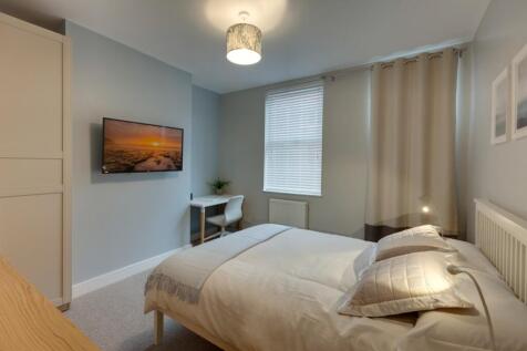 Bright, neatly styled master bedroom with a com...