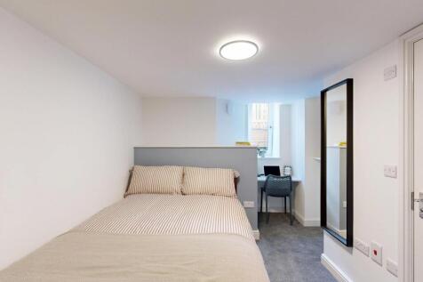 A bright and tidy bedroom featuring a comfortab...