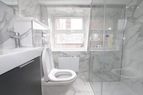 Modern marble-tiled bathroom with walk-in showe...