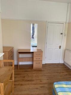 Bright bedroom with desk and wood-style floorin...