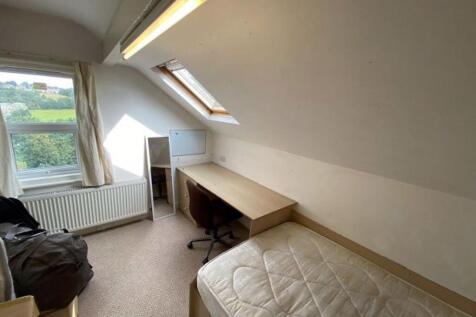 A cozy student bedroom featuring a single bed w...