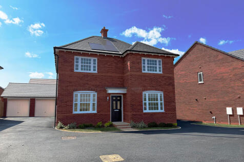 A red brick house with white-framed windows and solar panels on the roof sits on a paved driveway