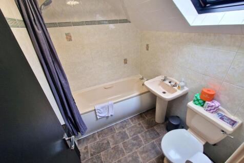 Bright, tiled bathroom with a full bath and ove...