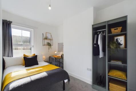 A modern, well-lit bedroom featuring a comforta...