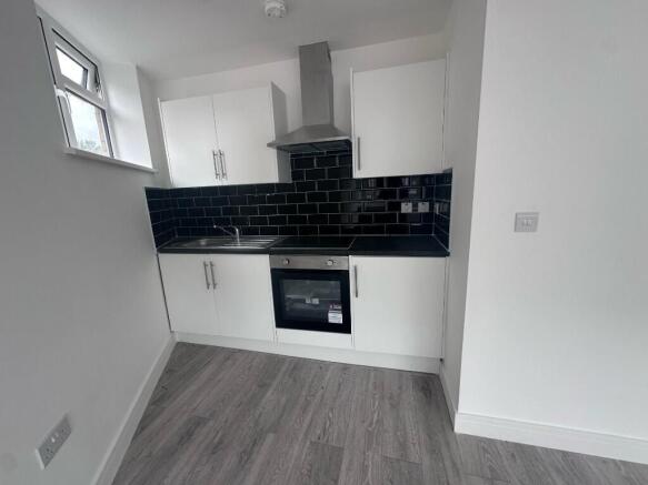 Modern compact kitchen with white cabinetry, in...