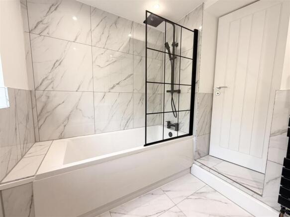 Elegant marble-tiled bathroom with modern bath ...
