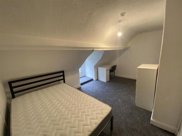 Bright attic bedroom with a desk and double bed...