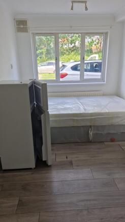 Bright bedroom with large window and wood floor...
