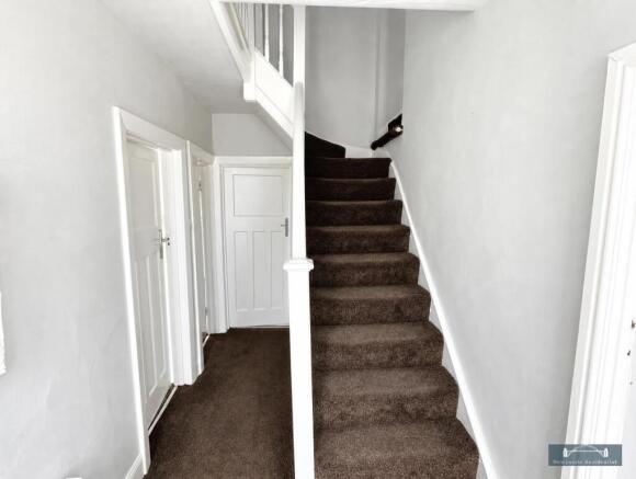 Bright, clean hallway with carpeted stairs...