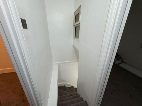 Compact painted stairwell with carpeted steps...