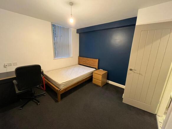 Neat single bedroom with a wooden bed frame, ma...
