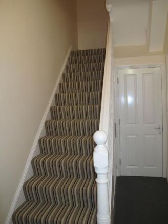Carpeted staircase with striped runner, white b...