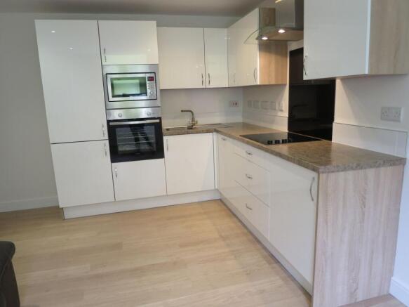 Modern kitchen featuring sleek white cabinetry,...