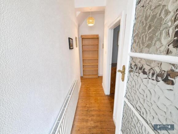 Clean hallway with wooden flooring and shelving...