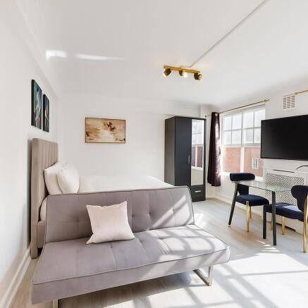 Bright, modern master suite with stylish sofa a...