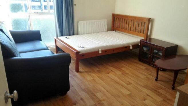 Bright bedroom with wooden floors and comfy sof...