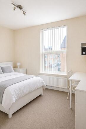 Bright bedroom with double bed and study desk a...