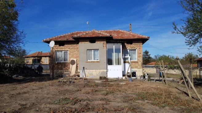 Front view of a small brick house with a tiled roof and enclosed porch in Gorotsvet village