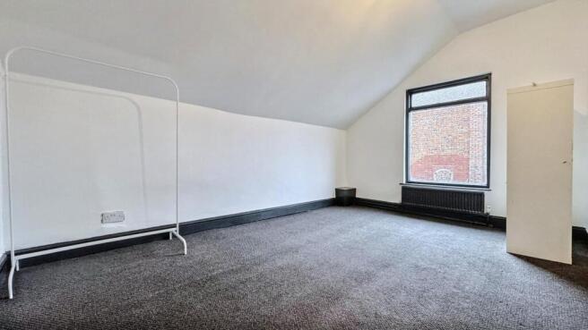 Bright, airy attic room with plush dark carpet....