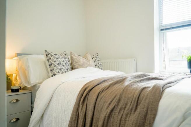 A bright and inviting double bedroom with styli...