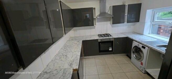 Bright modern kitchen with L-shaped marble-effe...